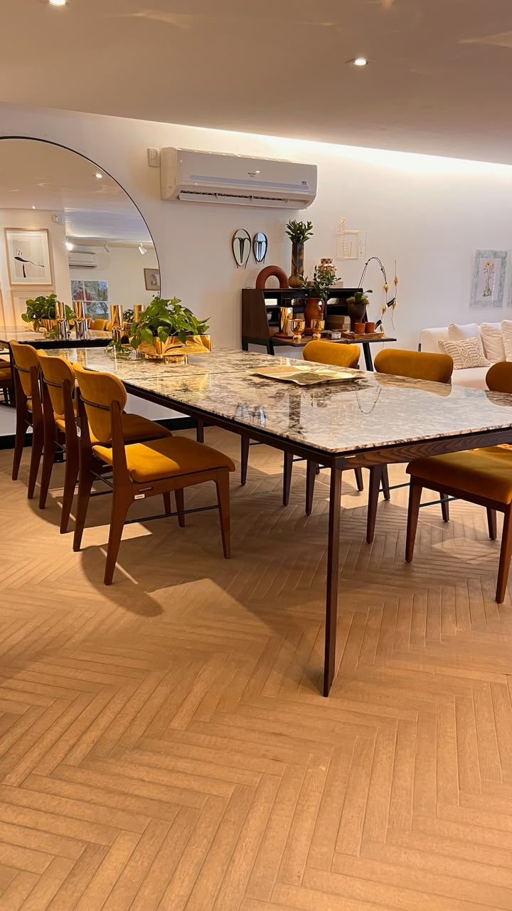 Sala de jantar com mesa em mármore e cadeiras estofadas mostarda